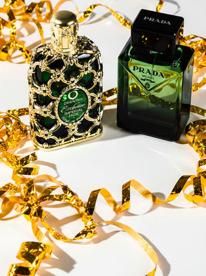 Two green luxury perfume bottles — Orientica Exclusive Imperial Jade and Prada Milano — styled with festive gold ribbon, showcasing new fragrance arrivals.