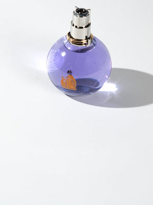 A round lavender-colored perfume bottle with a silver cap, on a white background, representing a budget-friendly fragrance option.