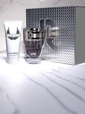 Paco Rabanne Invictus gift set with cologne, shampoo, and silver box displayed on a marble background.