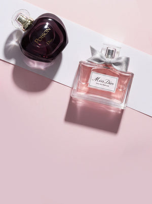 Dior Poison and Miss Dior perfume bottles on a soft pink background with elegant styling.