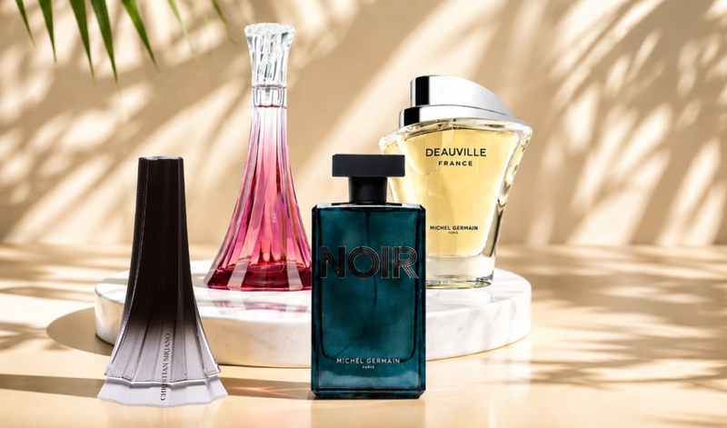 Four assorted perfume bottles displayed on a marble pedestal in warm sunlight.