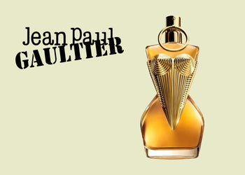 Jean Paul Gaultier perfume in a sculptural corset-style golden bottle, set against a pale green backdrop with bold black logo text. 2