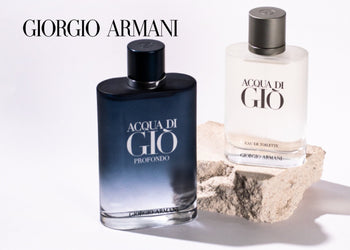 Two Giorgio Armani fragrances—Acqua di Giò Profondo in a deep blue bottle and Acqua di Giò Eau de Toilette in a frosted clear bottle—displayed on a minimalist white and stone background. 1