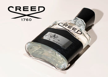 Creed Aventus cologne bottle displayed at an angle on a light background, highlighting its sleek design and iconic branding. 2