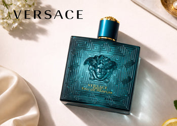 Versace Eros Eau de Parfum bottle on a soft ivory surface with flowers, citrus, and the Versace logo. 4
